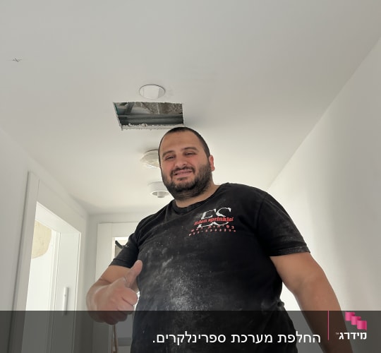 אדם עם חולצה מלוכלכת עומד בחדר עם תקרה פתוחה